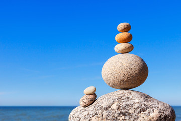 Rock zen pyramid of colorful pebbles on a beach on the background of the sea. Concept of balance, harmony and meditation.