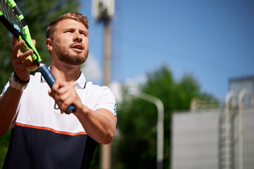 Caucasian bearded man playing tennis outdoors. Portrait of handsome tennis player with racket and...