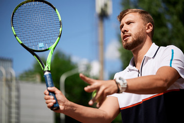 Young caucasian tennis player playing tennis and waiting for the service while standing on tennis...