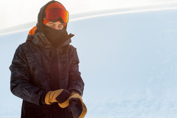 Young snowboarder in sportswear putting on his gloves before snowboarding. copy space. rest. free...