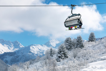 Fototapeta na wymiar skiers in chairlift above beautiful snowy winter landscape in french Alps