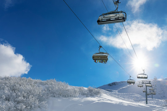 skiers in a ski lift in snowy mountains against blue sunny sky