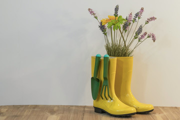 rain boots with gardening equipment and spring flowers on the eco background from sackcloth