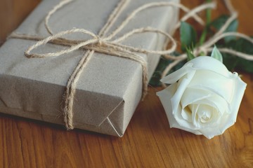 Brown eco friendly gift box decorated with soft pink and white rose on white wooden table, sweet lovely present valentine concept