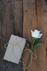 Brown eco friendly gift box decorated with soft pink and white rose on white wooden table, sweet lovely present valentine concept