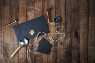 Vintage stationery mockup. Photo of blank black envelope, sealing wax, stamp, magnifier, compass...