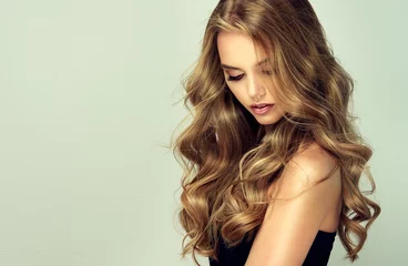 Photo sur Aluminium Salon de coiffure fille blonde aux cheveux ondulés longs et brillants. Beau modèle de femme souriante avec une coiffure frisée.