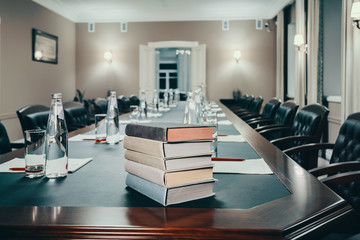 conference hall with books/ Books in small conference room with a large wooden table. Notebooks and mineral water on the table. Retro style