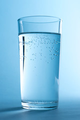 A glass of clean water in abstract blue lighr with air bubbles.