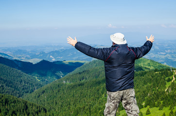 Man with spread arms in a joyful pose, in a mountain landscape