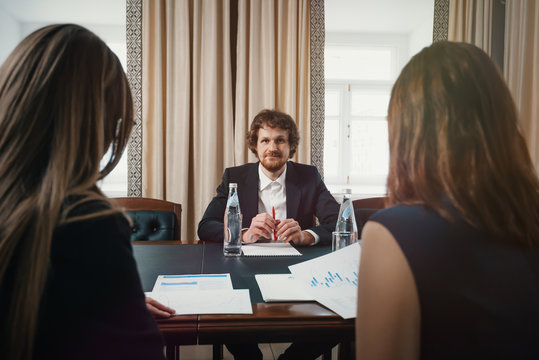 boss and employees/ Head talks to two subordinate girls about working in a business in a solid office