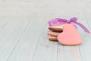 Painted gingerbread on a light wooden background. Tasty cookies in a forepe of hearts. There is for text. Love concept