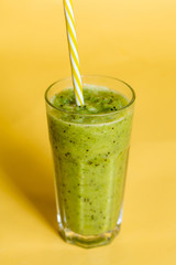 blended homemade green yoghurt in the glass. close up photo. isolated yellow background