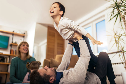 Happy family having fun on floor of in living room at home, laughing, selective focus.