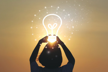 Creative idea and innovation concept, Woman hand holding light bulb on beautiful sunset background