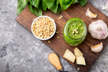 Pesto sauce in a bottle with ingredients (fresh basil, cheese, pine nuts, garlic)
