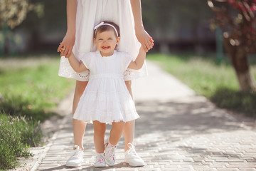 Unrecognizable Young attractive mother walking with her little cute daughter outdoor. Pretty family on the nature. Mom and her child having fun.