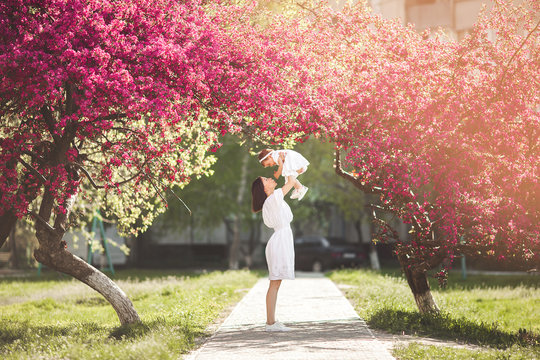 Young attractive mother walking with her little cute daughter outdoor. Pretty family on the nature. Mom and her child having fun. - Powered by Adobe