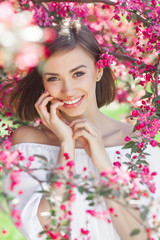 Obraz na płótnie Canvas Beauty portrait of young woman closeup. Attractive female in flowers with copy space. Beautiful lady outdoor.