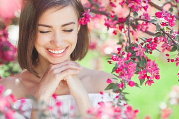 Beauty portrait of young woman closeup. Attractive female in flowers with copy space. Beautiful lady outdoor.