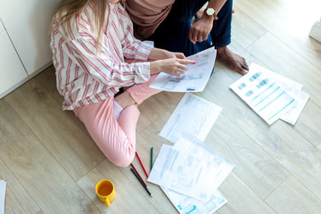 Interracial young couple of entepreneurs sharing ideas about new small business project, working at home with documents, planning new marketing concept, Small or family business collaboration concept