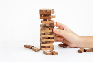hand pulling out or placing wood block on the tower in modern office, plan and strategy in business with white background.