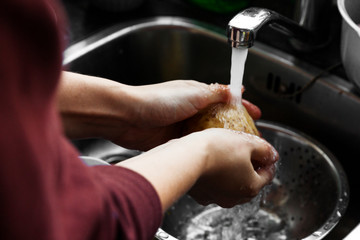 Hand washing potatoes in domestic kitchen sink.