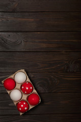 Happy Easter! Painted Easter eggs - red, white and red with white polka dots on a brown wooden background.