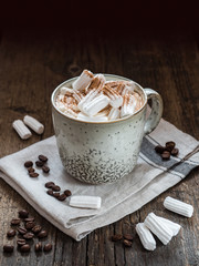 Large сup of coffee with milk and marshmallow sprinkled with cinnamon on a wooden table