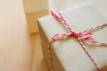 Vintage style picture of brown package box with red rope placed on a wooden table.