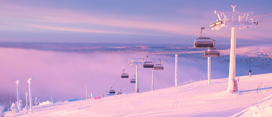 Panoramic view from the top of the mountain. Winter and sunrise. Skier on the ski slope.  Sunrise. Kuusamo Ruka. Finland Lapland.