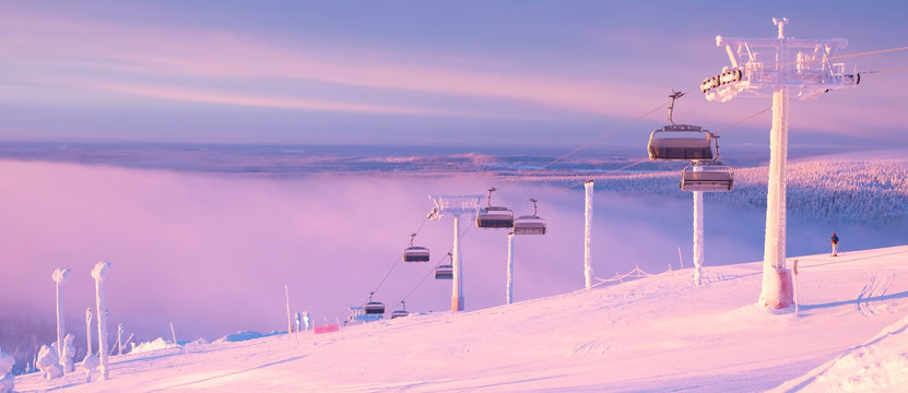 Panoramic view from the top of the mountain. Winter and sunrise. Skier on the ski slope.  Sunrise. Kuusamo Ruka. Finland Lapland.