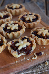 Mini Tartlets with dried fruits and nuts. Shortbread cookies with fruits stuffing on wooden background. Small sweet pie. Copy Space.