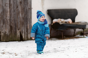 Smiling toddler in winter clothing with hat and scarf enjoying on the snow.