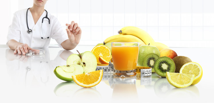 nutritionist doctor shows the pill in his hand at the desk office with fruits, tape meter and orange juice, healthy and balanced diet plan concept, web banner and copy space template