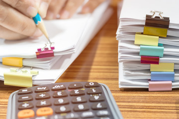 Teacher hand using pencil for checking students homework assignment on table office. Paper...