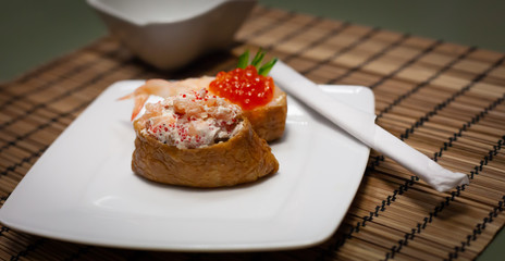 Omelette sushi with rice and salad with salmon, shrimps and caviar