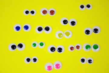 googly eyes on yellow pastel background,top view flat lay
