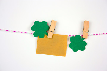 old vintage paper mock up and shamrock paper cut leaves on clothespin on white bakground