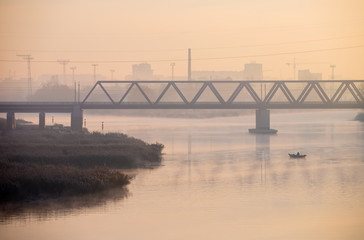 Railway bridge on the Odra River in Wroclaw with fisherman on boat at first plan