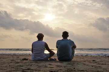 A romantic couple watching the sunset on a beach