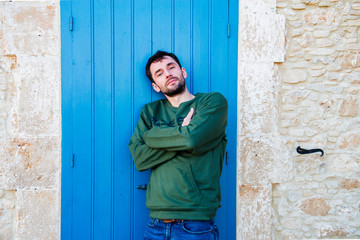 Obraz na płótnie Canvas The Greek man poses against the background of a blue door