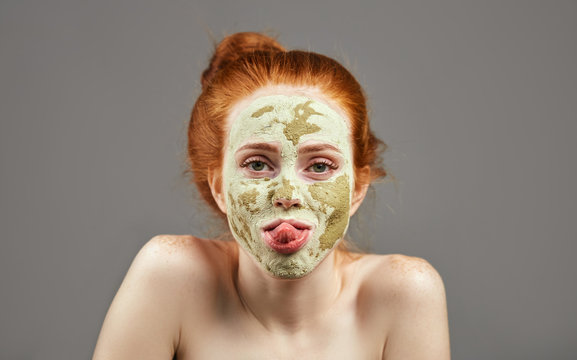 funny ginger girl with green mask showing her tongue. close up photo. studio shot.carzy girl sticking out her tongue
