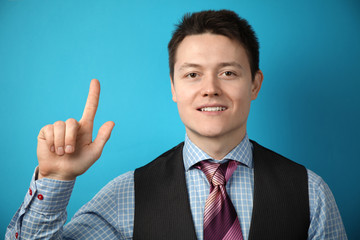 Adult businessman in suit on blue background points his finger at himself, smiling.