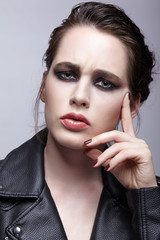 Fototapeta na wymiar Portrait of female in black leather jacket. Woman with unusual beauty evening makeup and violet - black shadows make-up.