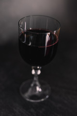 glass of intensely coloured red wine on dark background