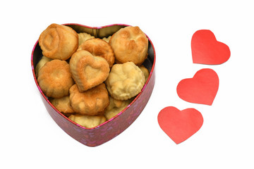 Isolate. Valentine's day. Box in the shape of a heart in it a lot of cupcakes, cookies, lie next to three red carved heart. Horizontal photography.