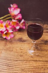 glass of intensely coloured red wine and tropical Australian flowers on wooden table