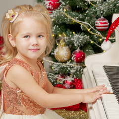 Little girl near the piano and Christmas tree.