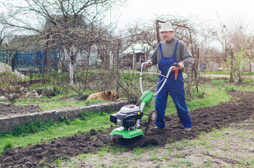 Man working in the spring garden with tiller machine
